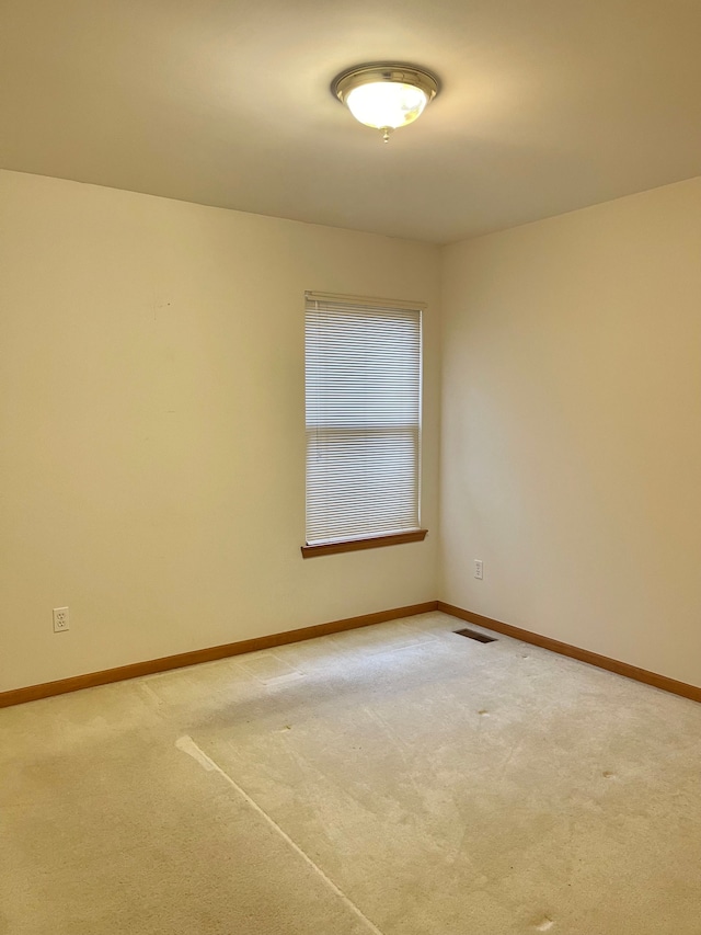 empty room featuring light carpet, baseboards, and visible vents