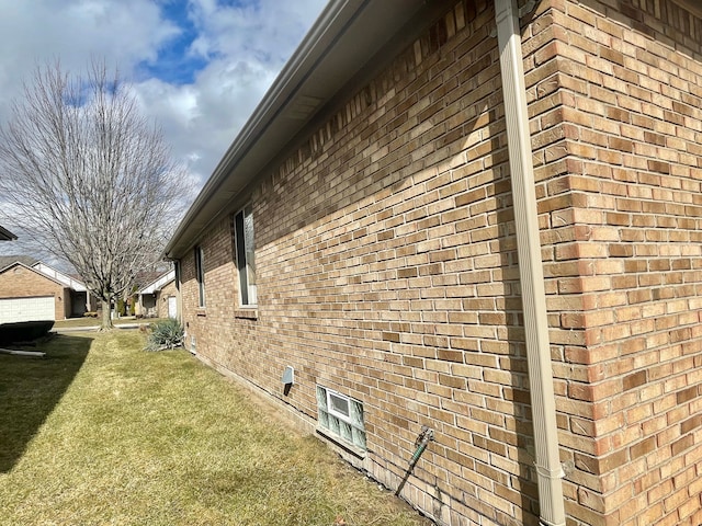 view of side of property with brick siding and a lawn