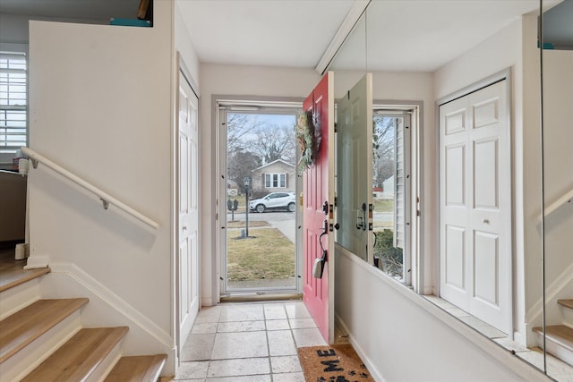 entryway with baseboards, stairway, and stone tile flooring