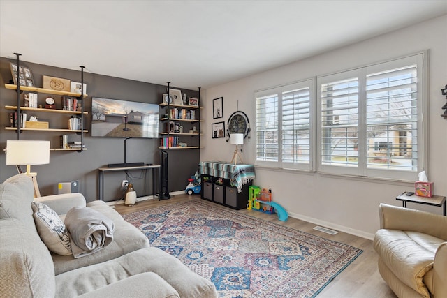 living room featuring visible vents, baseboards, and wood finished floors