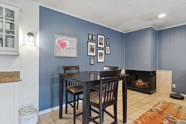 dining area with ornamental molding, baseboards, and a multi sided fireplace