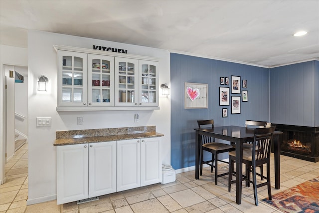 dining space featuring visible vents, a lit fireplace, baseboards, and stairs