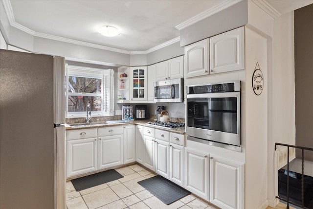 kitchen featuring stainless steel appliances, a sink, white cabinets, glass insert cabinets, and crown molding