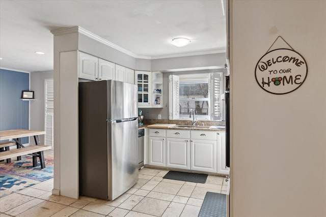 kitchen with a sink, white cabinets, appliances with stainless steel finishes, glass insert cabinets, and crown molding