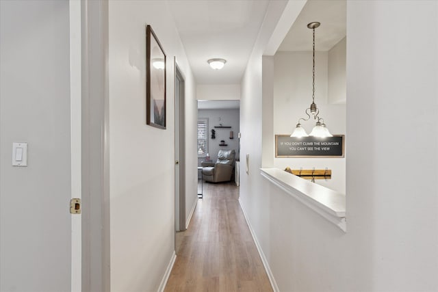 corridor featuring light wood-type flooring and baseboards