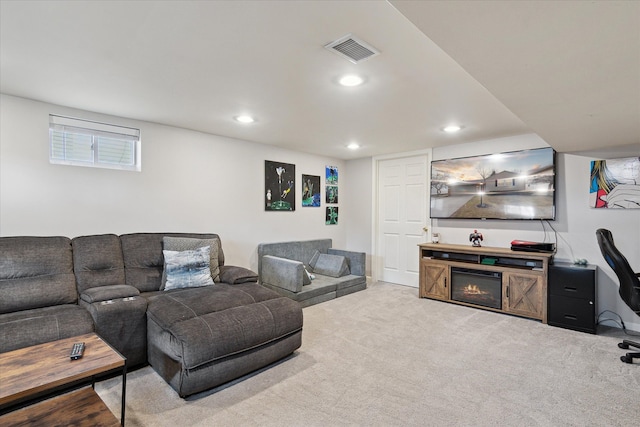 carpeted living room with a glass covered fireplace, visible vents, and recessed lighting