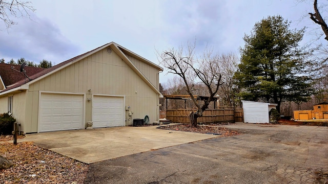 view of property exterior featuring driveway, a garage, and fence