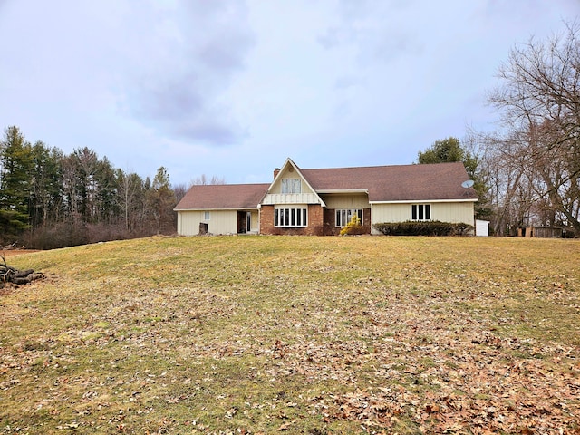 view of front facade with a front lawn, a chimney, and brick siding