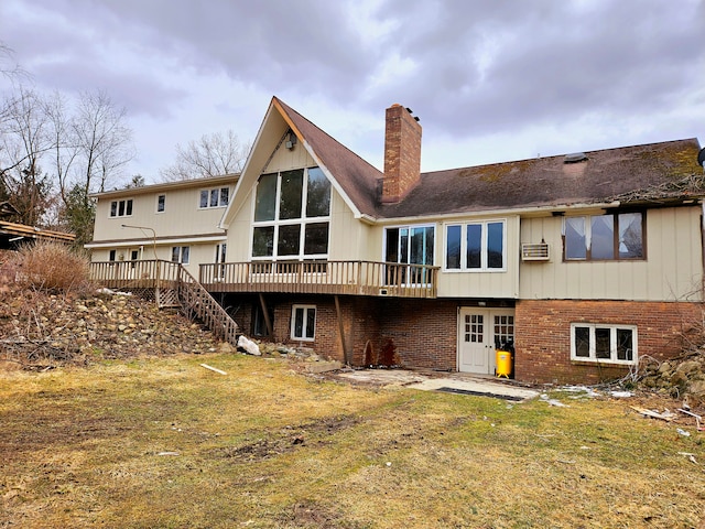 rear view of house with a deck, brick siding, a lawn, stairway, and a chimney