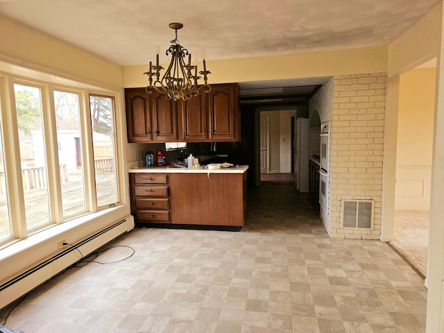 kitchen with a baseboard radiator, visible vents, light countertops, decorative light fixtures, and an inviting chandelier