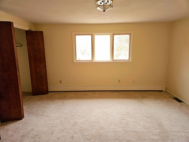 spare room featuring a baseboard heating unit, visible vents, and carpet flooring