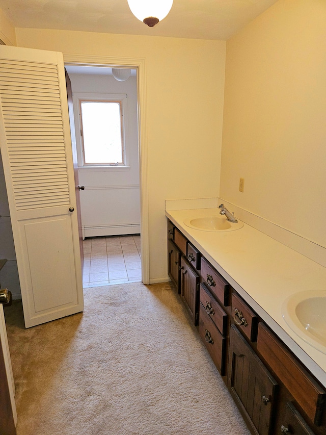 full bath featuring double vanity, tile patterned flooring, a baseboard radiator, and a sink