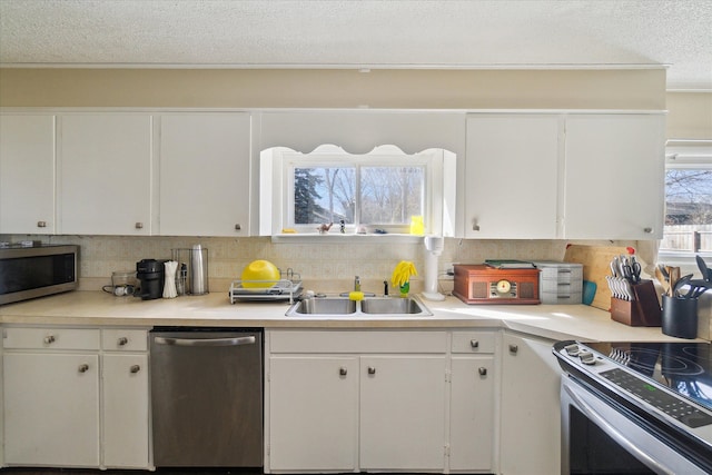 kitchen with light countertops, appliances with stainless steel finishes, a sink, and white cabinets