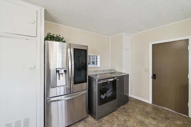 kitchen with stainless steel fridge, baseboards, a textured ceiling, and washing machine and dryer