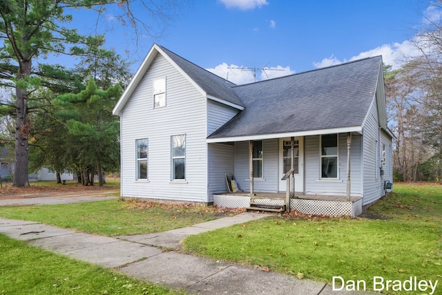 traditional-style home featuring covered porch, roof with shingles, and a front lawn