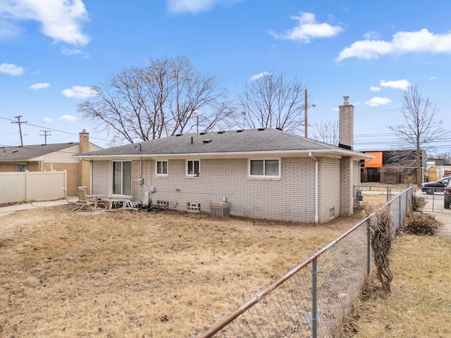 back of property with cooling unit, brick siding, a chimney, and a fenced backyard