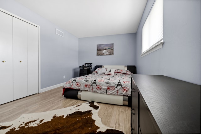 bedroom with baseboards, a closet, visible vents, and wood finished floors