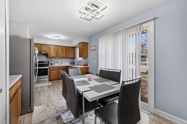 dining area featuring light wood finished floors, visible vents, and baseboards