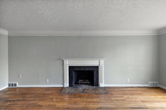 unfurnished living room with wood finished floors, a fireplace with flush hearth, and visible vents