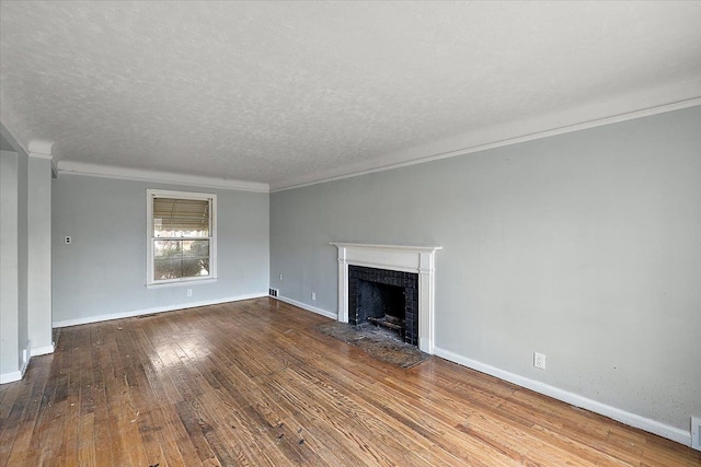 unfurnished living room featuring a textured ceiling, a fireplace with flush hearth, baseboards, ornamental molding, and wood-type flooring