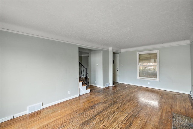 spare room with visible vents, wood-type flooring, stairs, a textured ceiling, and crown molding