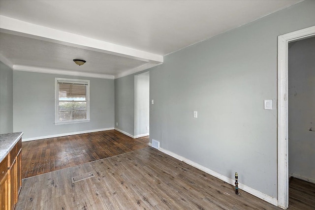 spare room featuring baseboards, visible vents, and hardwood / wood-style floors