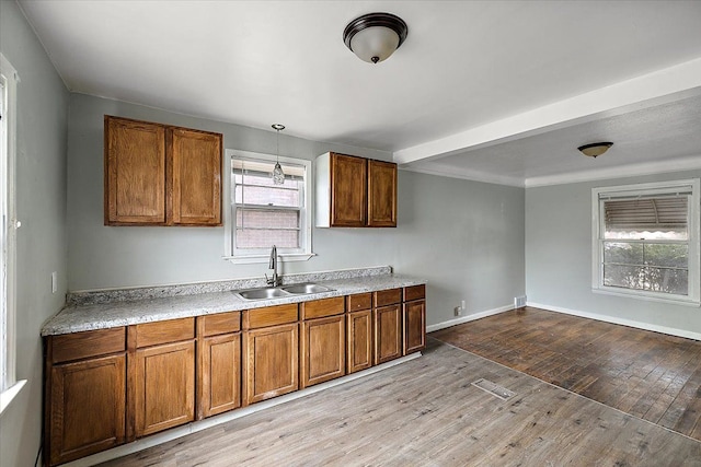 kitchen featuring light wood-type flooring, brown cabinetry, and a sink