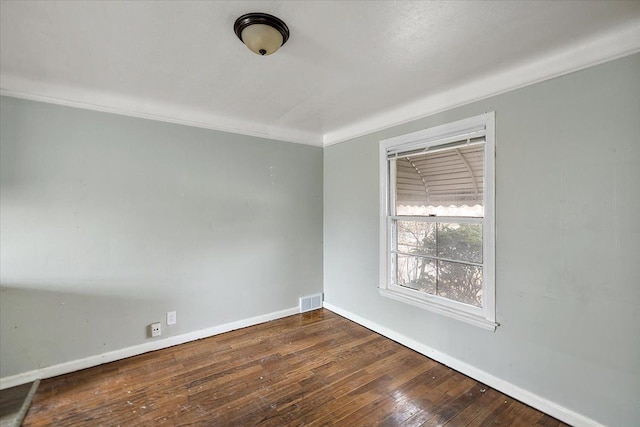 empty room with baseboards, visible vents, crown molding, and hardwood / wood-style floors