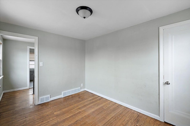 spare room with visible vents, baseboards, and wood finished floors