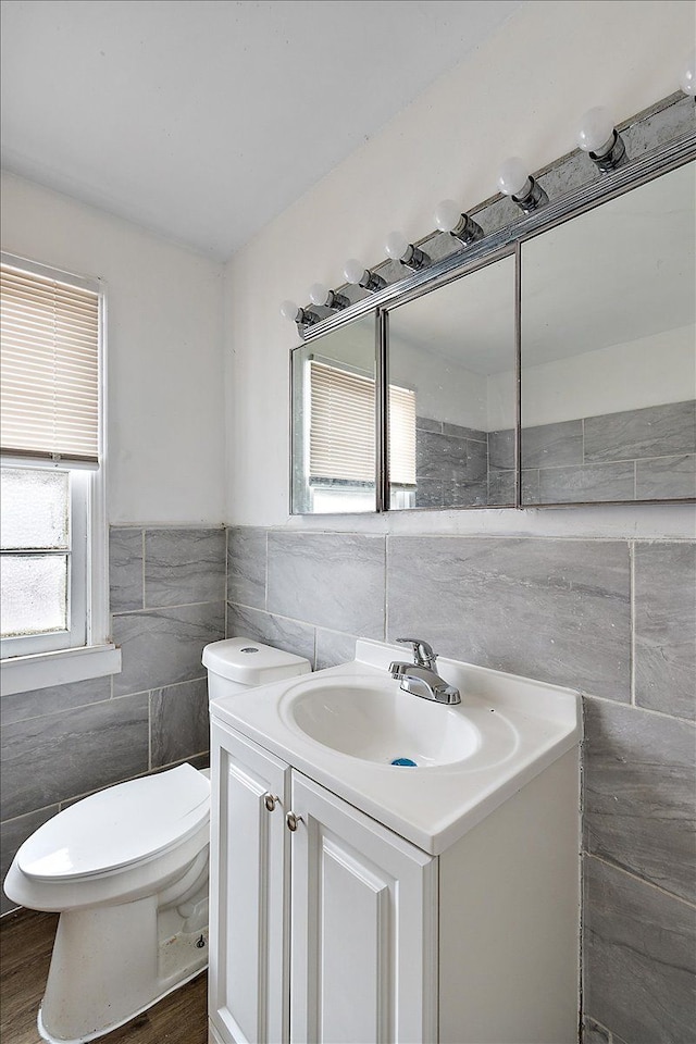 half bath with toilet, tile walls, and vanity