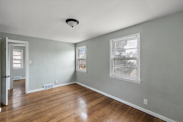 unfurnished room with wood finished floors, visible vents, and a healthy amount of sunlight