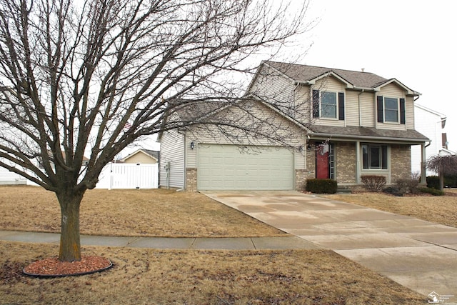 traditional-style house with an attached garage, fence, concrete driveway, and brick siding