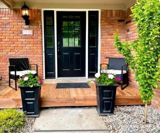 entrance to property with covered porch and brick siding