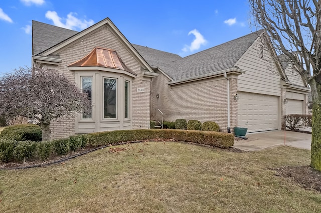 view of front of property featuring a shingled roof, concrete driveway, and brick siding