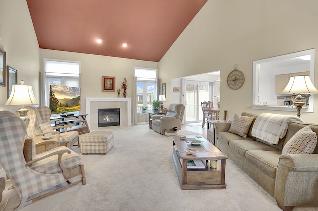 carpeted living room with high vaulted ceiling and a tiled fireplace