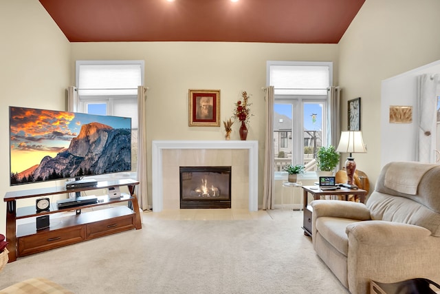 living area featuring lofted ceiling, a tile fireplace, and carpet flooring