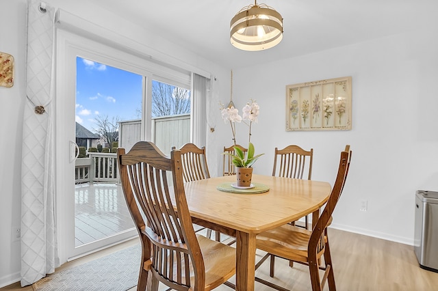 dining area with light wood-type flooring and baseboards