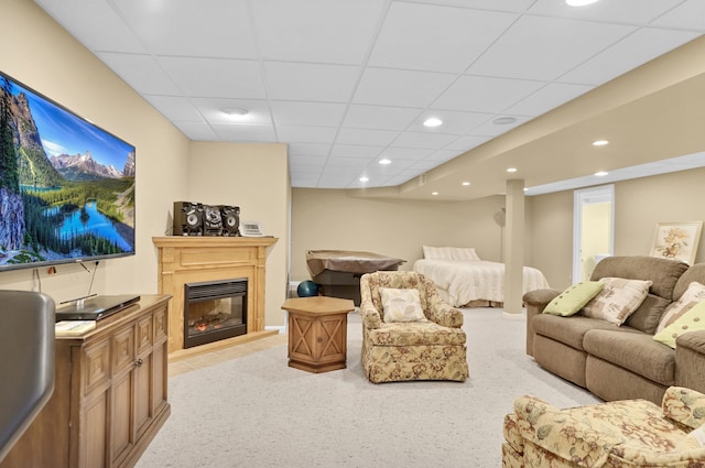 living room featuring light carpet, a drop ceiling, a glass covered fireplace, and recessed lighting