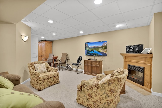 living area featuring carpet, recessed lighting, a glass covered fireplace, a drop ceiling, and baseboards