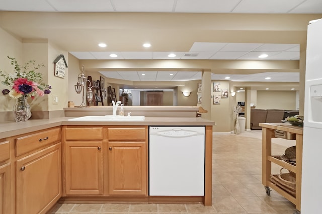 kitchen with white dishwasher, a peninsula, a sink, visible vents, and open floor plan