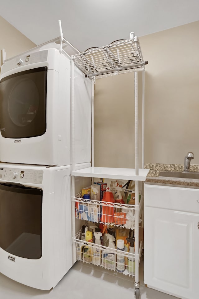 clothes washing area with stacked washing maching and dryer, a sink, and cabinet space