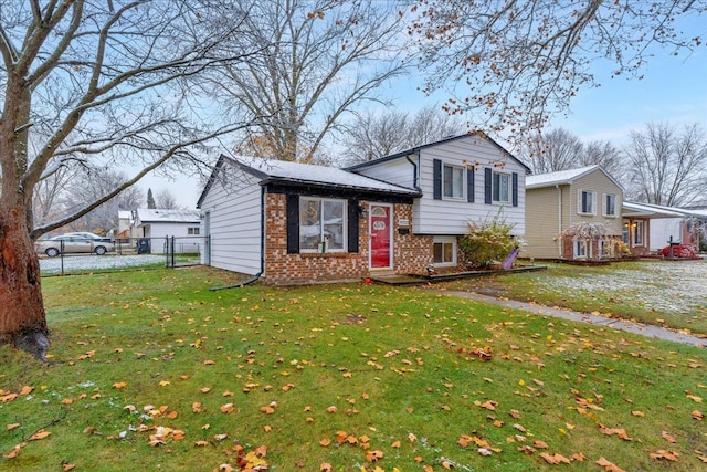 split level home featuring brick siding, a front lawn, fence, and a gate