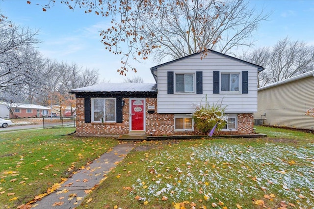 split level home featuring a front yard, central AC, and brick siding