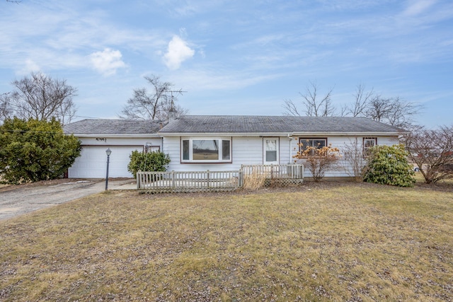 ranch-style home featuring driveway, an attached garage, and a front yard