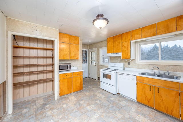 kitchen featuring brown cabinets, white appliances, light countertops, and a sink