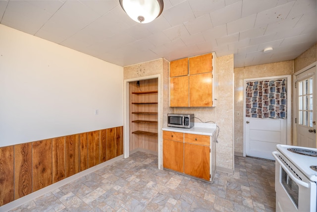 kitchen with built in shelves, light countertops, wainscoting, stainless steel microwave, and white electric range oven