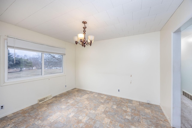 unfurnished room with stone finish floor, visible vents, a notable chandelier, and baseboards