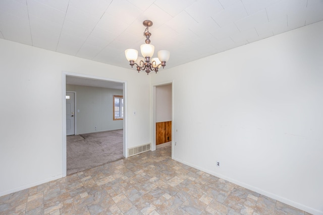 unfurnished room with a chandelier, stone finish floor, visible vents, and baseboards