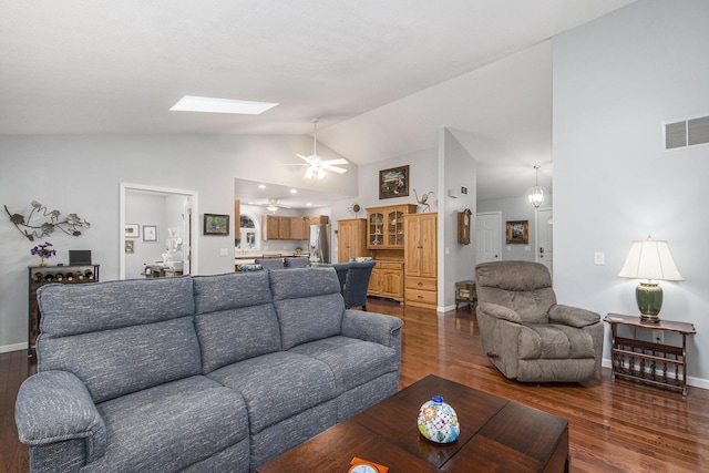 living room with vaulted ceiling with skylight, dark wood-style flooring, visible vents, and baseboards