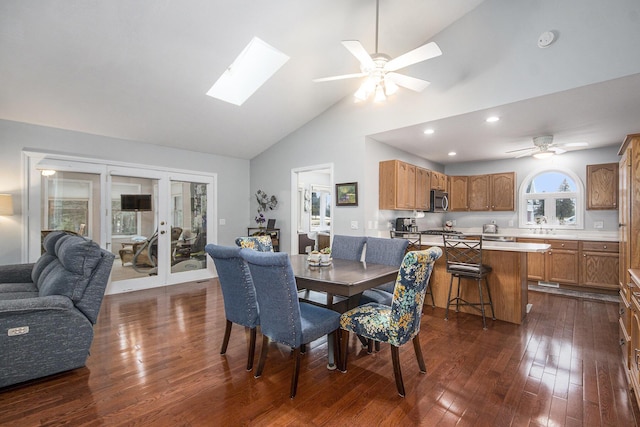 dining space with a skylight, french doors, dark wood finished floors, a ceiling fan, and high vaulted ceiling